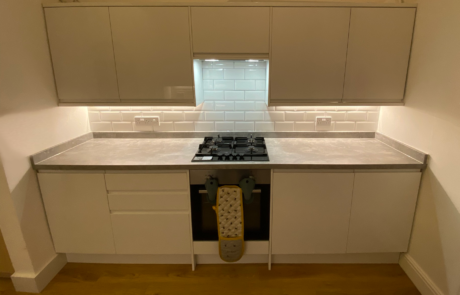 Modern kitchen by Hummingbird Bathrooms and Kitchens featuring white cabinets, classic subway tile splashback, gas cooker and oven with oven gloves on the handle, and warm under-cabinet lighting illuminating the worktop; expert kitchen design and construction services in the UK. Modern kitchen by Hummingbird Bathrooms and Kitchens featuring white cabinets, classic subway tile splashback, gas cooker and oven with oven gloves on the handle, and warm under-cabinet lighting illuminating the worktop; expert kitchen design and construction services in the UK.