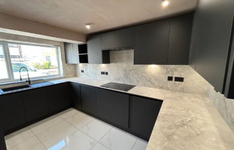 Contemporary kitchen designed by Hummingbird Bathrooms and Kitchens featuring matt black cupboards, light marble worktops, built-in hob, tiled flooring, under-cupboard lighting, and a large window above the sink providing natural daylight—expert kitchen design and installation services in the UK. Contemporary kitchen designed by Hummingbird Bathrooms and Kitchens featuring matt black cupboards, light marble worktops, built-in hob, tiled flooring, under-cupboard lighting, and a large window above the sink providing natural daylight—expert kitchen design and installation services in the UK.